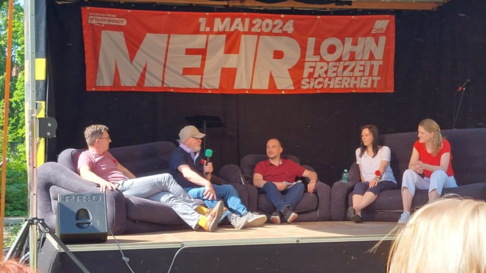 Personen auf dem Podium diskutieren zum 1. Mai